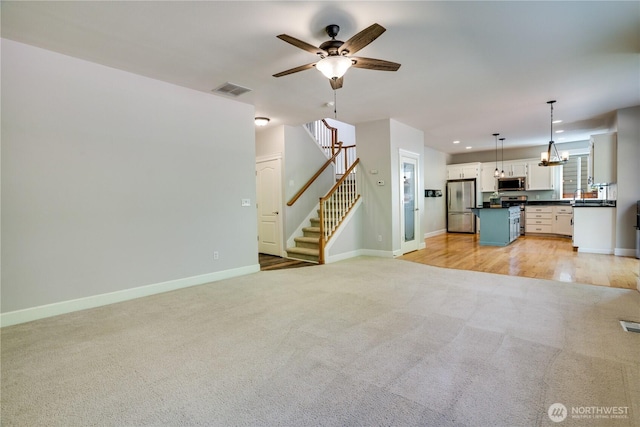 20313 194th Ave E, Orting, WA 98360 - unfurnished living room with light colored carpet, a ceiling fan, stairway, recessed lighting, and a chandelier