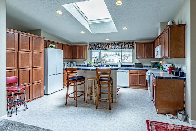 17612 19th Ave E Unit 83, Spanaway, WA 98387 - kitchen featuring white appliances, a skylight, light colored carpet, a textured ceiling, and a kitchen breakfast bar