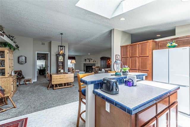 17612 19th Ave E Unit 83, Spanaway, WA 98387 - kitchen with freestanding refrigerator, carpet flooring, brown cabinets, a kitchen island, and a skylight