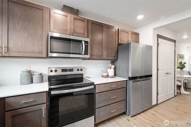 1339 Nolta Loop NE, Bainbridge Island, WA 98110 - kitchen with stainless steel appliances, light countertops, light wood-style flooring, dark brown cabinetry, and recessed lighting