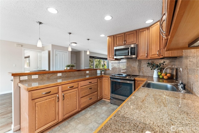 201 Pennsylvania Ave Unit 15, Wenatchee, WA 98801 - kitchen featuring stainless steel appliances, tile countertops, a peninsula, brown cabinetry, and tasteful backsplash