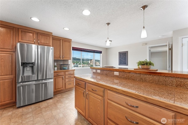 201 Pennsylvania Ave Unit 15, Wenatchee, WA 98801 - kitchen featuring stainless steel fridge with ice dispenser, tile counters, brown cabinetry, hanging light fixtures, and a textured ceiling