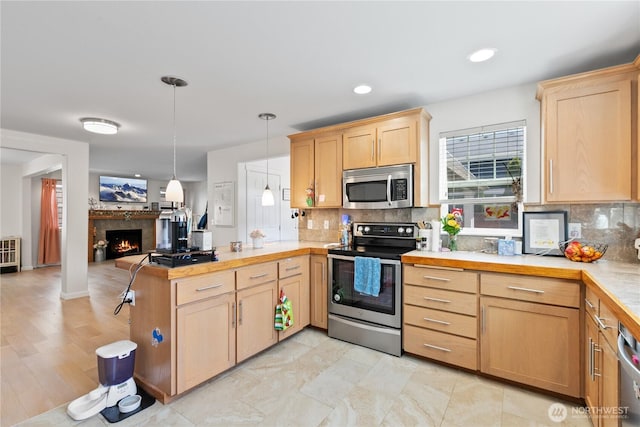 6974 Prism St SE, Lacey, WA 98513 - kitchen featuring appliances with stainless steel finishes, a peninsula, light brown cabinetry, open floor plan, and tasteful backsplash