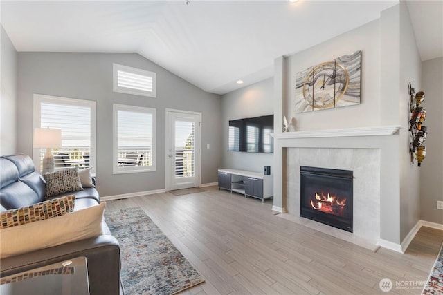 7103 Hazel Pl SE, Auburn, WA 98092 - living room featuring lofted ceiling, wood finished floors, a tile fireplace, and healthy amount of natural light