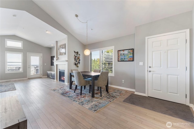 7103 Hazel Pl SE, Auburn, WA 98092 - dining area with vaulted ceiling, healthy amount of natural light, a warm lit fireplace, and wood finished floors