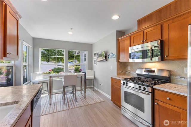 7103 Hazel Pl SE, Auburn, WA 98092 - kitchen featuring stainless steel appliances, decorative backsplash, light wood-style floors, brown cabinetry, and recessed lighting