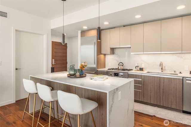 800 Columbia St Unit 2309, Seattle, WA 98104 - kitchen featuring appliances with stainless steel finishes, decorative backsplash, dark wood finished floors, a kitchen bar, and recessed lighting