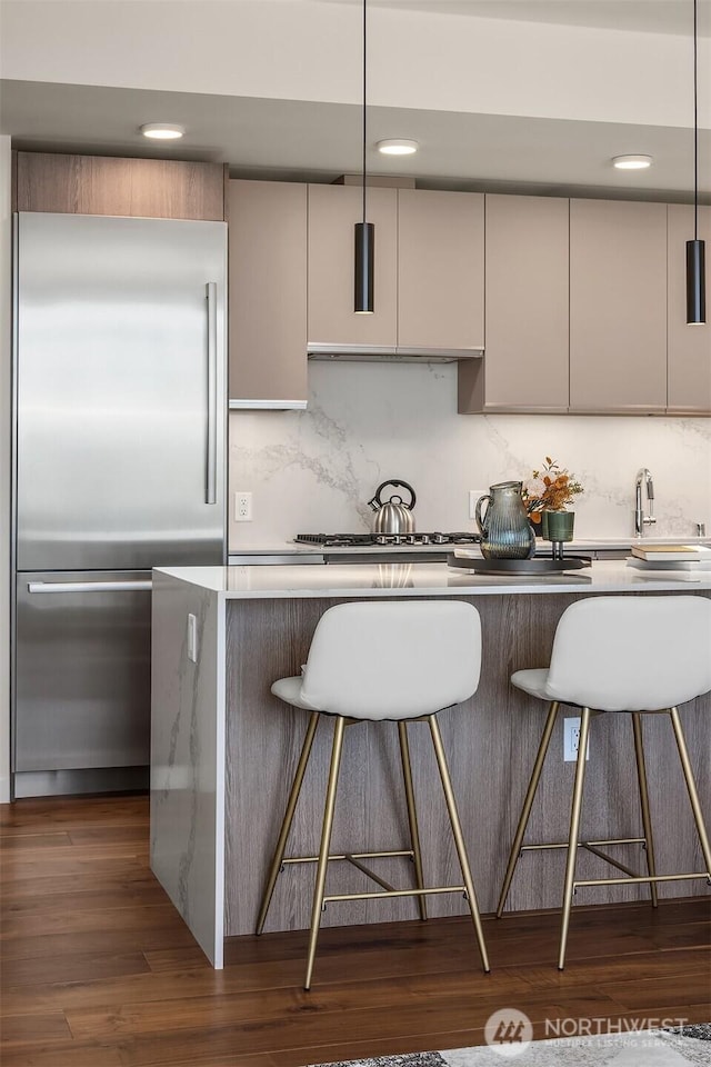 800 Columbia St Unit 2309, Seattle, WA 98104 - kitchen with stainless steel appliances, tasteful backsplash, a breakfast bar area, dark wood-style floors, and recessed lighting