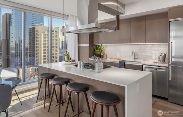 800 Columbia St Unit 2503, Seattle, WA 98104 - kitchen with island range hood, stainless steel appliances, modern cabinets, a kitchen bar, and light countertops