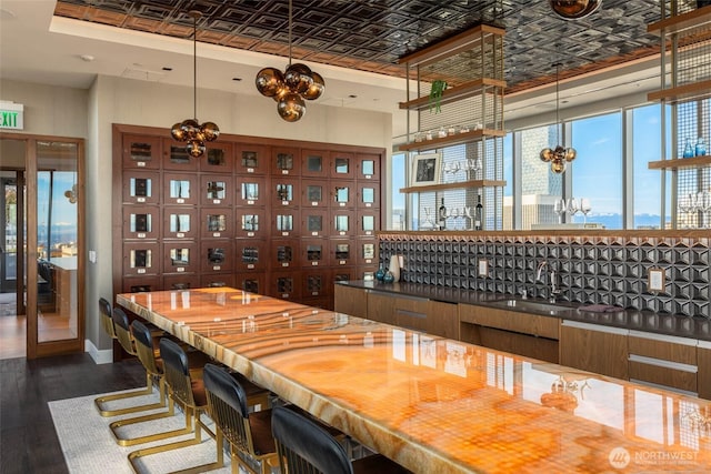 800 Columbia St Unit 2503, Seattle, WA 98104 - bar area featuring an ornate ceiling, dark wood-type flooring, a chandelier, decorative light fixtures, and a tray ceiling