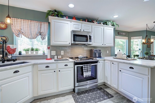 12118 261st Ave E, Buckley, WA 98321 - kitchen featuring stainless steel appliances, a peninsula, light wood-type flooring, white cabinetry, and recessed lighting