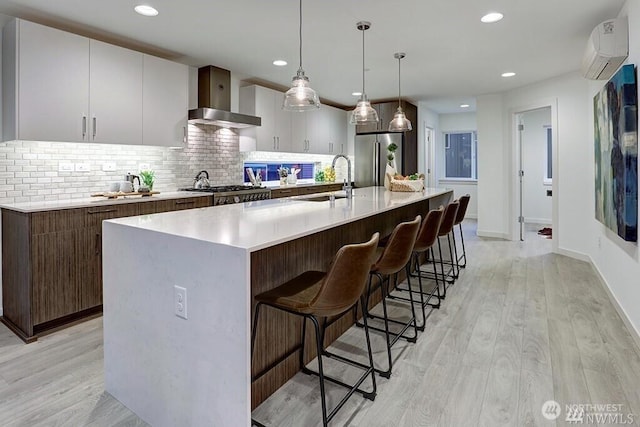 8707 116th Ave NE Unit A, Kirkland, WA 98033 - kitchen with wall chimney range hood, freestanding refrigerator, light wood-style floors, an AC wall unit, and backsplash