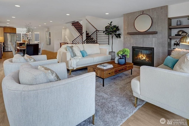 8707 116th Ave NE Unit A, Kirkland, WA 98033 - living room featuring stairway, light wood-style floors, a large fireplace, a chandelier, and recessed lighting