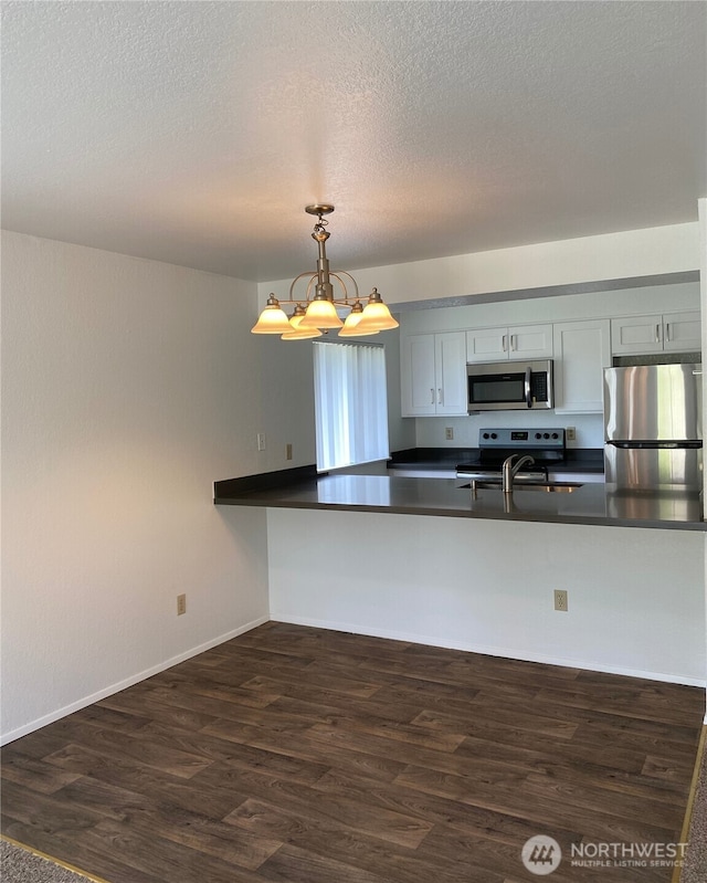 6003 Broadway, Everett, WA 98203 - kitchen featuring stainless steel appliances, dark countertops, dark wood-style flooring, a chandelier, and hanging light fixtures