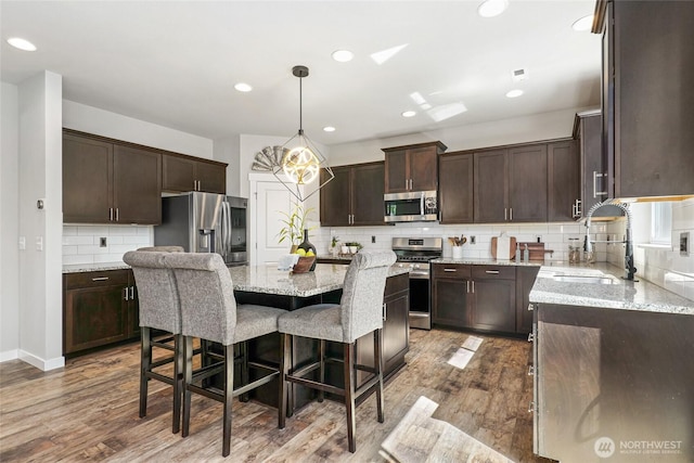 1705 85th Ave SE, Lake Stevens, WA 98258 - kitchen with stainless steel appliances, dark brown cabinetry, tasteful backsplash, a breakfast bar, and a kitchen island