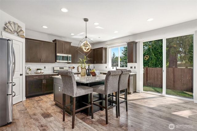 1705 85th Ave SE, Lake Stevens, WA 98258 - kitchen featuring appliances with stainless steel finishes, dark brown cabinets, light wood finished floors, decorative backsplash, and recessed lighting