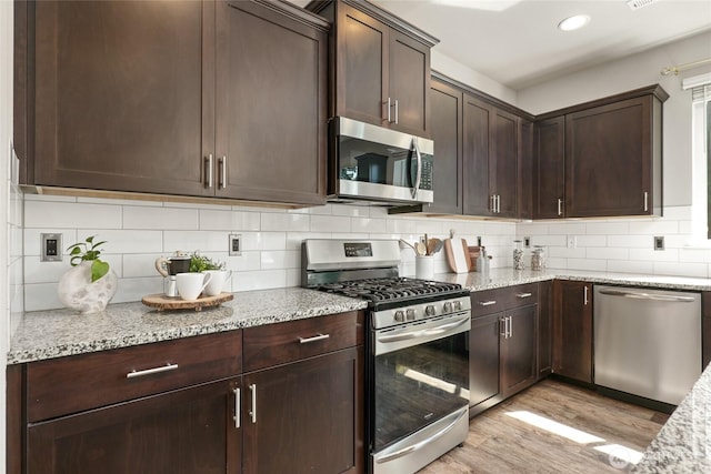 1705 85th Ave SE, Lake Stevens, WA 98258 - kitchen with stainless steel appliances, light wood-type flooring, dark brown cabinetry, light stone countertops, and tasteful backsplash