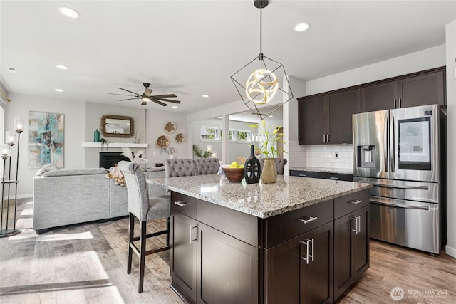 1705 85th Ave SE, Lake Stevens, WA 98258 - kitchen featuring stainless steel fridge with ice dispenser, light wood-style floors, dark brown cabinets, a ceiling fan, and decorative backsplash