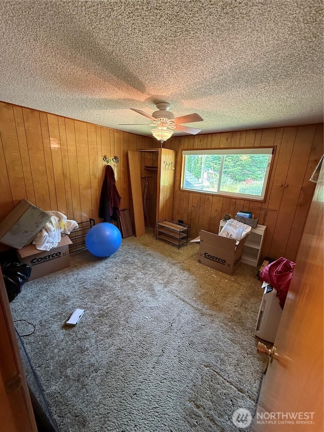 5645 Lento Pl SE, Olympia, WA 98513 - unfurnished bedroom with a textured ceiling, wooden walls, carpet, and a ceiling fan