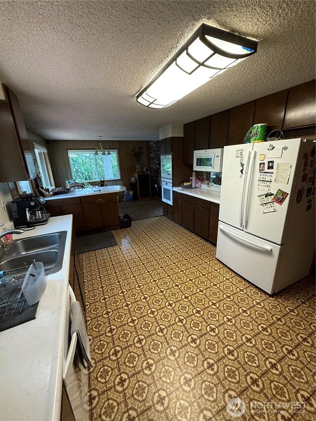 5645 Lento Pl SE, Olympia, WA 98513 - kitchen featuring white appliances, a textured ceiling, light countertops, dark brown cabinets, and wooden walls