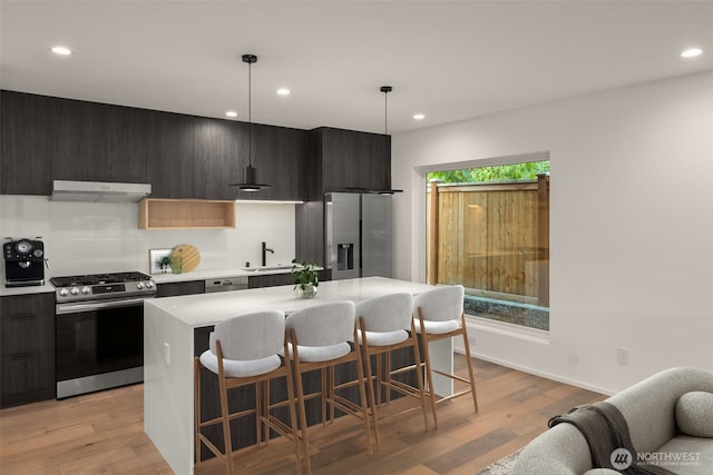 926 23rd Ave, Seattle, WA 98122 - kitchen featuring stainless steel appliances, under cabinet range hood, modern cabinets, a kitchen bar, and recessed lighting