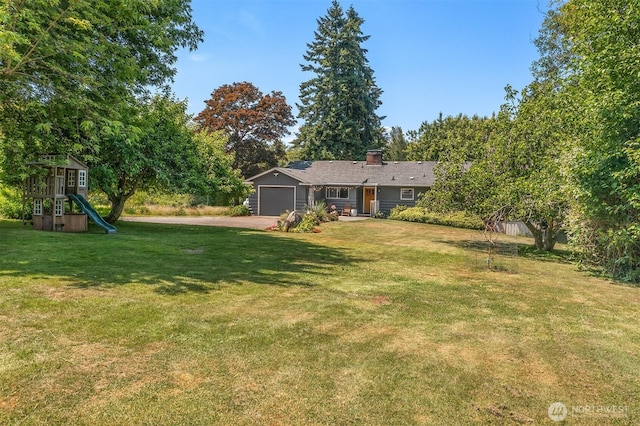 16305 Crescent Dr SW, Vashon, WA 98070 - view of green lawn with asphalt driveway, a garage, and a playground