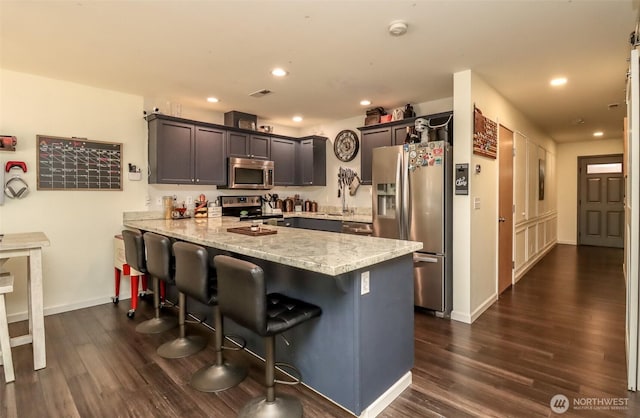 6530 Newaukum Pl NE, Bremerton, WA 98311 - kitchen with stainless steel appliances, a peninsula, dark wood-type flooring, light stone countertops, and a breakfast bar