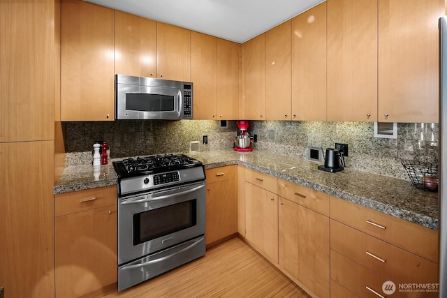 17 W Mercer St Unit 300, Seattle, WA 98119 - kitchen with appliances with stainless steel finishes, light wood finished floors, tasteful backsplash, and stone countertops