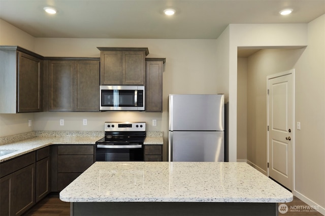 2309 158th Street Ct E, Tacoma, WA 98445 - kitchen with stainless steel appliances, dark brown cabinets, dark wood-style floors, a kitchen island, and light stone countertops