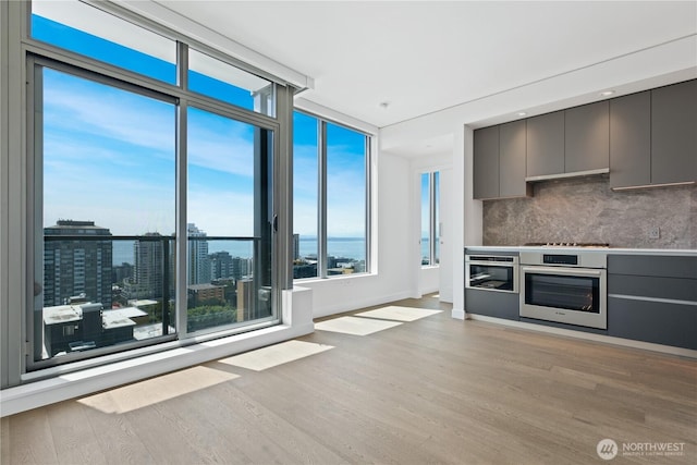 2510 6th Ave Unit 2306, Seattle, WA 98121 - kitchen featuring stainless steel oven, gray cabinetry, backsplash, light wood-style flooring, and modern cabinets