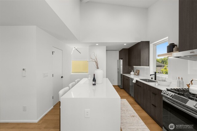 930 23rd Ave, Seattle, WA 98122 - kitchen featuring modern cabinets, appliances with stainless steel finishes, dark brown cabinets, a towering ceiling, and a kitchen island