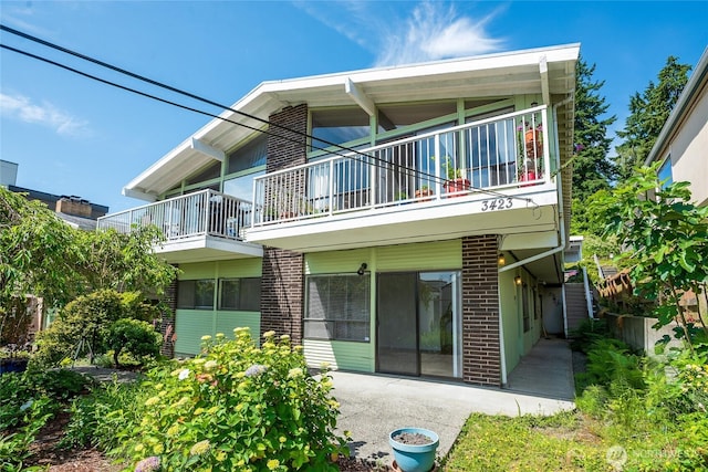 3421 23rd Ave W, Seattle, WA 98199 - back of property with a balcony, brick siding, and a patio