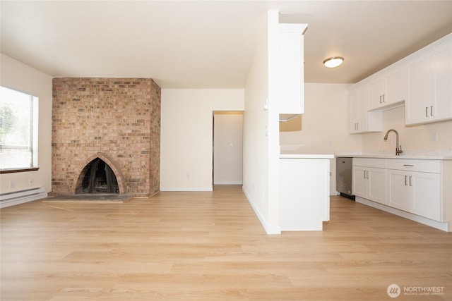3421 23rd Ave W, Seattle, WA 98199 - kitchen with open floor plan, light wood-style floors, light countertops, white cabinets, and a fireplace