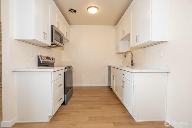 3421 23rd Ave W, Seattle, WA 98199 - kitchen featuring stainless steel appliances, light wood-style flooring, and white cabinets