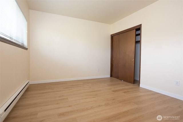 3421 23rd Ave W, Seattle, WA 98199 - unfurnished bedroom featuring a baseboard heating unit, light wood-style floors, and a closet