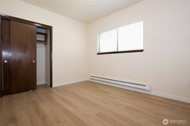 3421 23rd Ave W, Seattle, WA 98199 - unfurnished bedroom with baseboard heating, light wood finished floors, and a closet