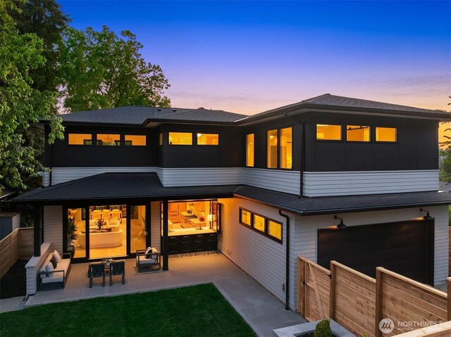 7008 29th Ave NE, Seattle, WA 98115 - back of house at dusk with a garage, a patio area, and board and batten siding