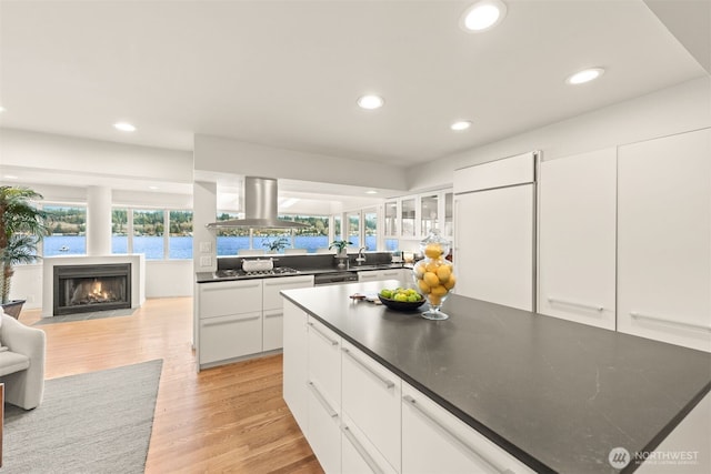 5438 E Mercer Way, Mercer Island, WA 98040 - kitchen with island range hood, light wood-type flooring, dark countertops, recessed lighting, and a fireplace with flush hearth