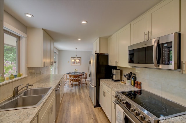 27521 U St, Ocean Park, WA 98640 - kitchen with stainless steel appliances, light wood finished floors, light countertops, white cabinets, and decorative backsplash