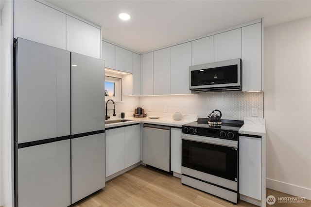 4839 S Holly St, Seattle, WA 98118 - kitchen with stainless steel appliances, white cabinetry, tasteful backsplash, light wood-style flooring, and recessed lighting