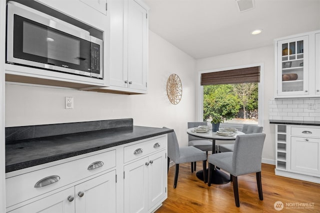 1424 E 36th Ln, Bellingham, WA 98226 - kitchen featuring stainless steel microwave, dark countertops, light wood-type flooring, glass insert cabinets, and recessed lighting