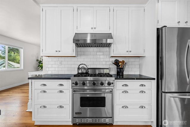 1424 E 36th Ln, Bellingham, WA 98226 - kitchen featuring stainless steel appliances, range hood, dark countertops, and decorative backsplash
