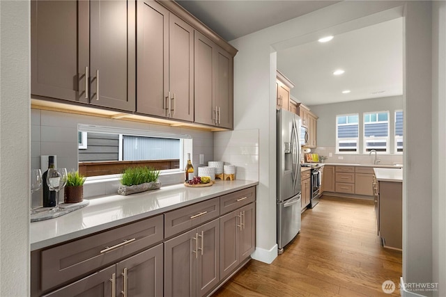 18611 134th St E, Bonney Lake, WA 98391 - kitchen with appliances with stainless steel finishes, light wood-style floors, decorative backsplash, recessed lighting, and light countertops