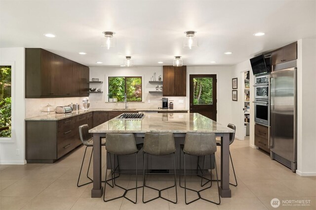 25112 SE 17th St, Sammamish, WA 98075 - kitchen featuring stainless steel appliances, open shelves, dark brown cabinetry, a kitchen breakfast bar, and recessed lighting