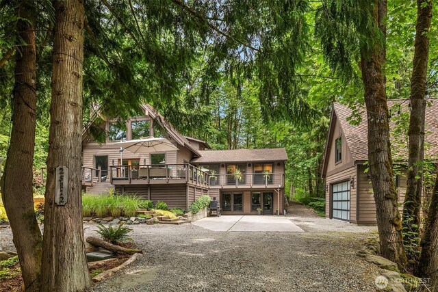 25112 SE 17th St, Sammamish, WA 98075 - rear view of property featuring gravel driveway, a wooden deck, an attached garage, a shingled roof, and an outdoor structure