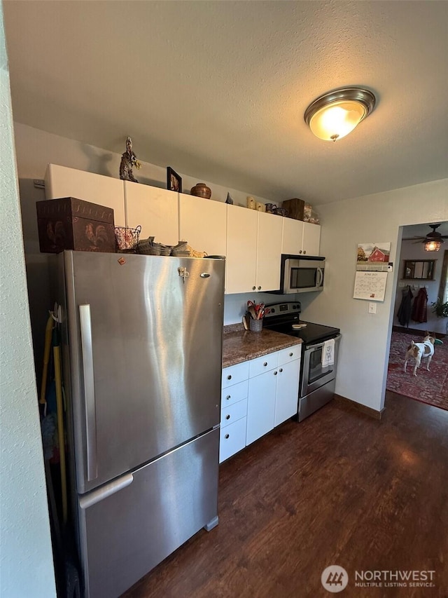 416 Cedar St S, Omak, WA 98841 - kitchen featuring stainless steel appliances, dark wood finished floors, white cabinetry, dark countertops, and a textured ceiling