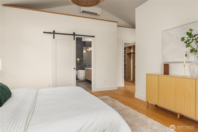 4615 2nd Ave NE, Seattle, WA 98105 - bedroom with a barn door, wood finished floors, a spacious closet, a wall mounted AC, and vaulted ceiling