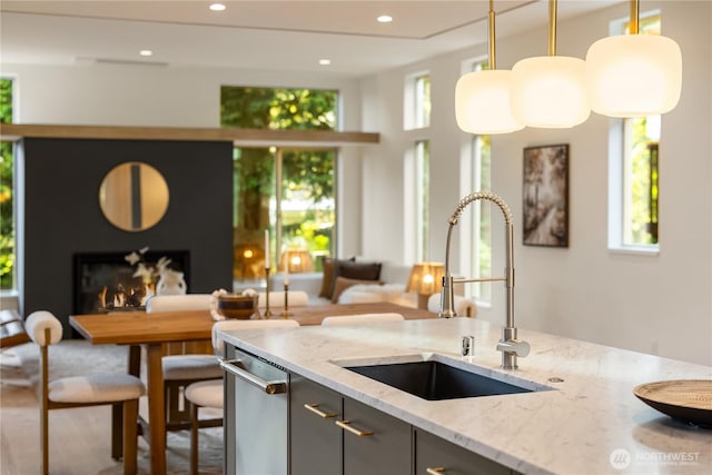 4615 2nd Ave NE, Seattle, WA 98105 - kitchen with healthy amount of natural light, decorative light fixtures, light stone countertops, a lit fireplace, and recessed lighting