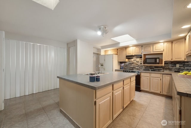 8718 Dresden Ln SW, Lakewood, WA 98498 - kitchen with white fridge with ice dispenser, tile counters, stainless steel gas stove, black microwave, and a skylight
