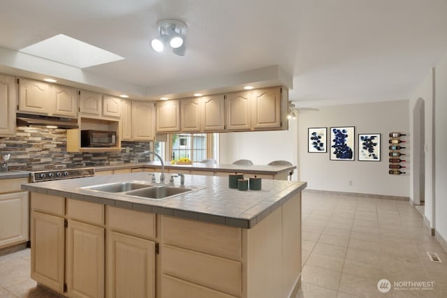 8718 Dresden Ln SW, Lakewood, WA 98498 - kitchen featuring tile counters, backsplash, under cabinet range hood, black microwave, and a skylight